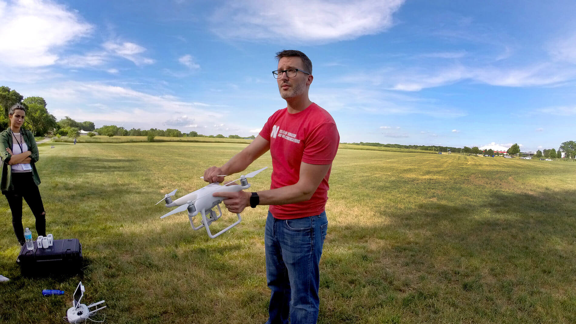 Waite holding a drone while demonstrating in a grassy field during a workshop.