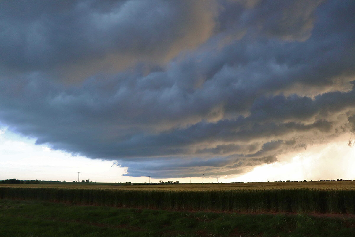 A massive dark cloud bank dominates an otherwise bright sky.